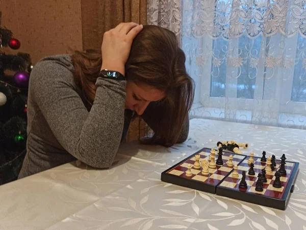 Upset european woman play chess at table