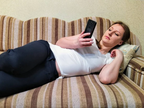Εστιασμένη Ευρωπαϊκή Κοπέλα Ξαπλωμένη Στον Καναπέ Και Χρησιμοποιούν Smartphone Στο — Φωτογραφία Αρχείου