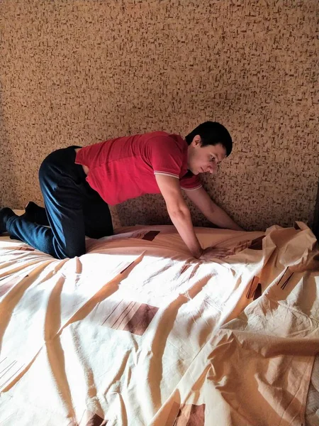 European man cover bedsheet on mattress in bedroom