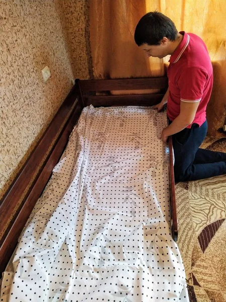 European man cover bedsheet on mattress on baby bed in bedroom