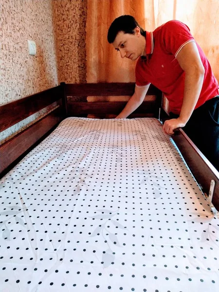 European man cover bedsheet on mattress on baby bed in bedroom