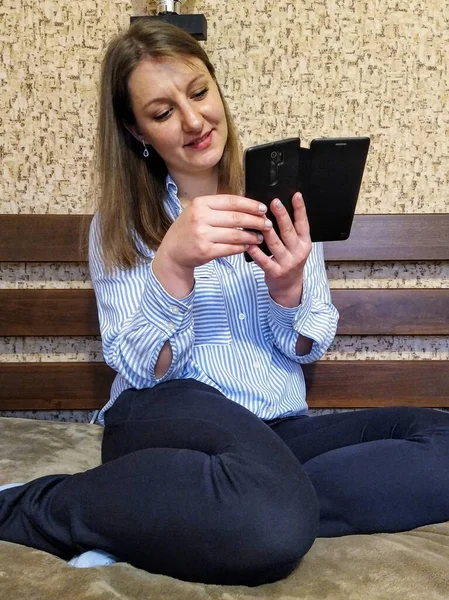 Χαμογελώντας Ευρωπαϊκή Γυναίκα Κάθονται Στο Κρεβάτι Και Χρησιμοποιήσετε Smartphone Στο — Φωτογραφία Αρχείου