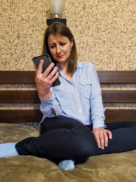 Αναστατωμένη Ευρωπαϊκή Γυναίκα Κάθεται Στο Κρεβάτι Και Χρησιμοποιήσετε Smartphone Στο — Φωτογραφία Αρχείου