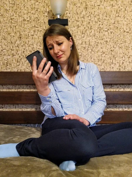 Αναστατωμένη Ευρωπαϊκή Γυναίκα Κάθεται Στο Κρεβάτι Και Χρησιμοποιήσετε Smartphone Στο — Φωτογραφία Αρχείου