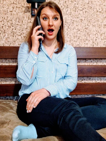 Chockad Europeisk Kvinna Sitta Sängen Och Prata Smartphone Sovrummet Hemma — Stockfoto