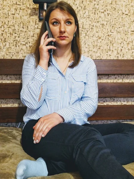 Εστιασμένη Ευρωπαία Γυναίκα Κάθεται Στο Κρεβάτι Και Μιλάει Στο Smartphone — Φωτογραφία Αρχείου