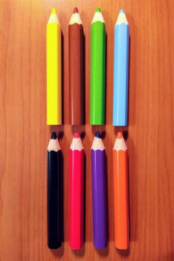 Ahşap arka planda renkli sanat kalemleri.