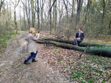 Fotoğrafçı, Avrupalı kadını Spring Forest 'ta akıllı telefondan fotoğraflıyor.