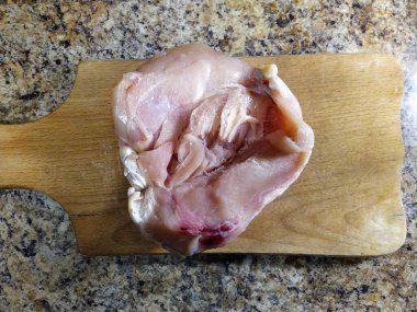 Tavuk filetosunun mutfak masasındaki kesim tahtasının üst görüntüsü.