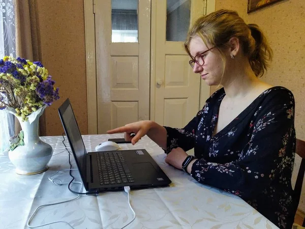 유럽의 여성은 테이블에 앉아서 비디오 통화를 노트북 컴퓨터에 손가락으로 가리키며 — 스톡 사진