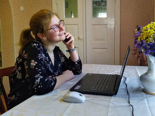 Щаслива Молода Жінка Сидить Столом Говорить Смартфоні Працює Вдома Ноутбуку — стокове фото