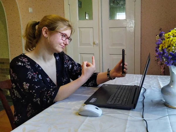 ヨーロッパの若い女性はテーブルに座り ビデオ通話をし 自宅でスマートフォンで中指を表示します — ストック写真