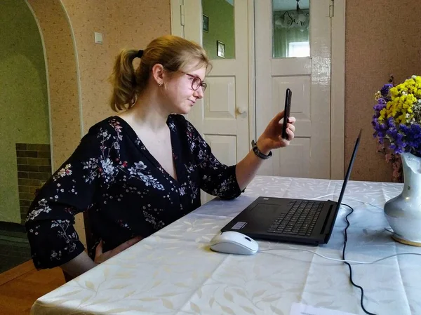 腰に手を持つヨーロッパの若い女性はテーブルに座って 自宅でスマートフォンでビデオ通話を持っています — ストック写真