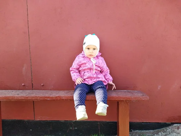 European Toddler Girl Sit Wooden Bench Background Red Fence — Stock Photo, Image