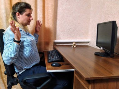 Hüsrana uğramış Avrupalı genç kadın masada oturup evdeki bilgisayarda çalışıyor.