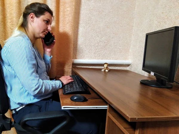 Skoncentrowana Młoda Europejka Siedzi Przy Stole Rozmawia Smartfonie Pracuje Komputerze — Zdjęcie stockowe