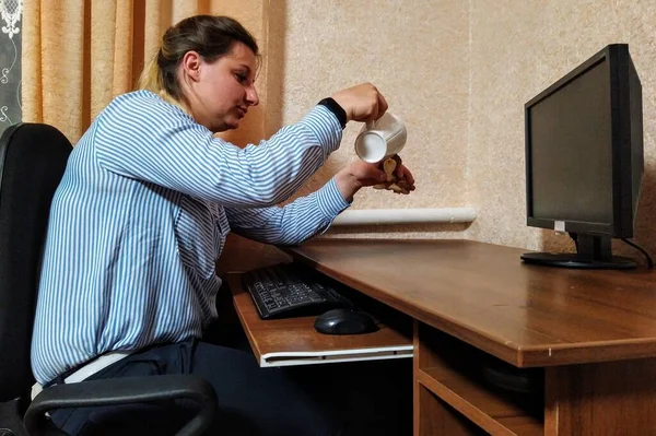 ヨーロッパの若い女性はテーブルに座って カップとスタチューで遊び 自宅でコンピュータ上で動作します — ストック写真
