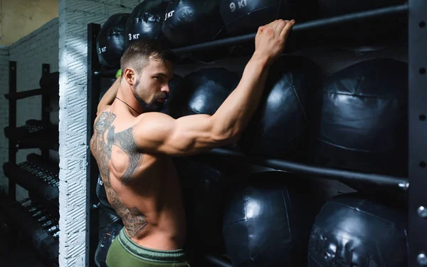 Posando atleta com tatuagem em um fundo de equipamento esportivo — Fotografia de Stock