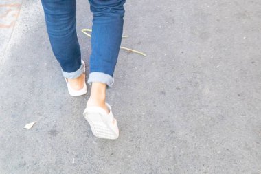 Beton yolda yürüyen kişinin arka görünüşü.