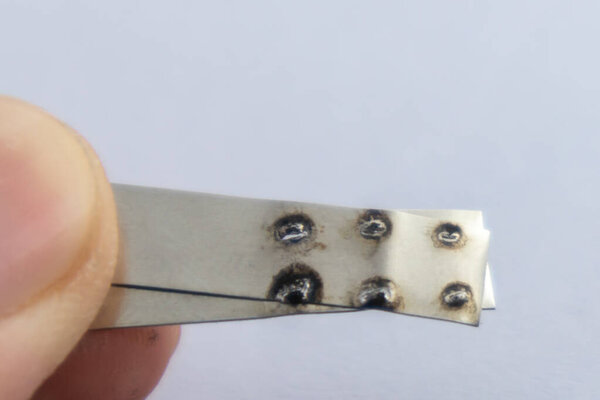 Spot welding on nickel strip with blurred background.