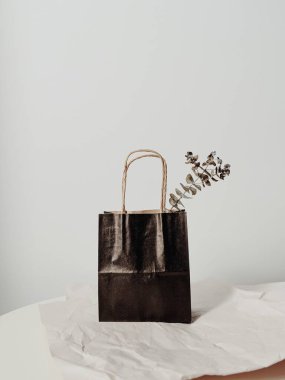 Okaliptüs dallı siyah bir alışveriş poşeti ve buruşuk kağıt arka planlı bir masa. Asgari düzeyde. Moda tasarımı. Boşluk konseptini kopyala.