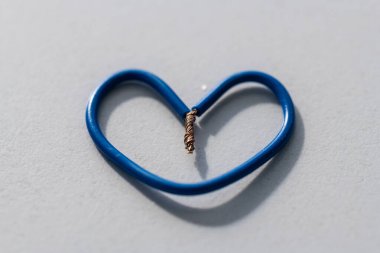 Gri arkaplanda mavi kablolardan yapılmış küçük bir kalp.