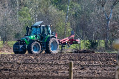 Hude, Almanya 6 Nisan 2020: Bir traktör araçlarıyla yeni temizlenmiş bir alanda duruyor