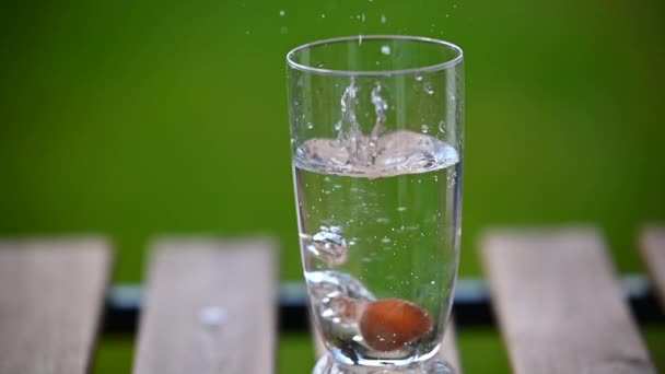 Une noisette tombe dans un verre d'eau au ralenti 