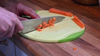 Birisi keskin bir bıçakla bir tahtanın üzerinde havucu küçük parçalara ayırıyor.