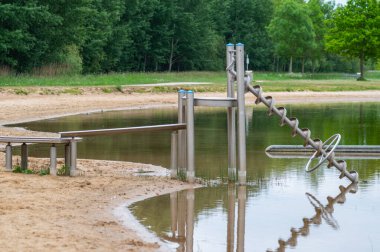 Kazılmış bir göl manzarası ve özellikle çocuklar için yansıtıcı bir oyuncak Kuzey Almanya 'da bulutlu gökyüzü ve sakin su ile kıyıdan su taşıyabilen