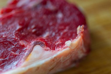 Dilimlenmiş taze bir biftek ve ahşap bir tahtanın üzerinde yağlı biftek.