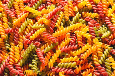 Pişmemiş üç renkli fusilli makarna kıvrımlı arka plan şeklini alır. Stok fotoğraf makarna büküm şekilleri.