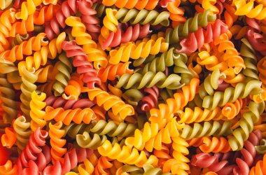 Pişmemiş üç renkli fusilli makarna kıvrımlı arka plan şeklini alır. Stok fotoğraf makarna büküm şekilleri.