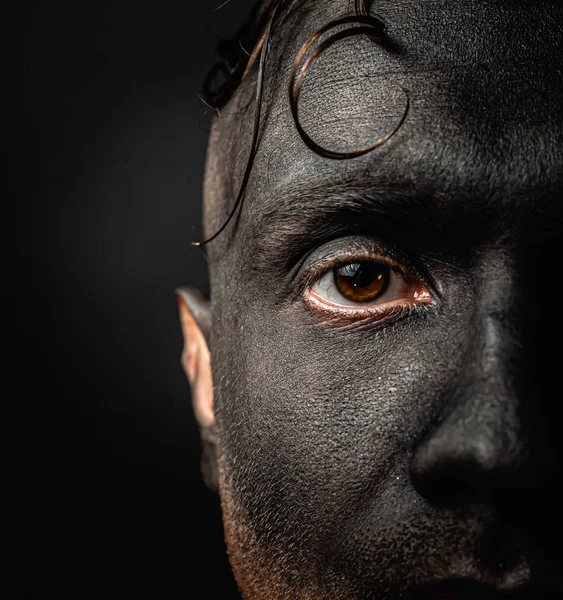 The dirty face of a working miner. Close-up portrait of a black face in soot. Stock photo.