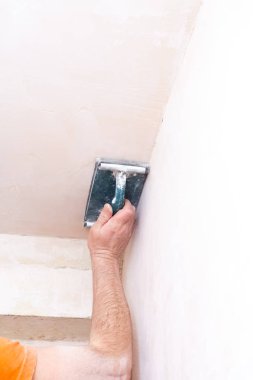 Sıvacı duvarları zımpara kağıdıyla kaplıyor. Bir işçinin erkek eli. Stok fotoğrafı.