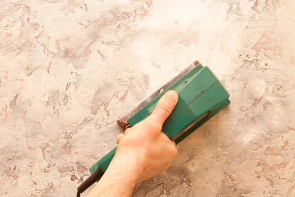 Electronic grinder in a hand. Grinding and leveling the surface of the walls. — Stock Image Electronic Grinder Hand Grinding Leveling Surface Walls Stock Picture