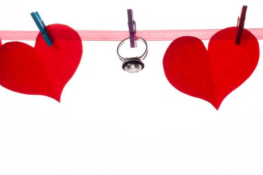 Beyaz arka plandaki mandallarda kırmızı kağıt kalpler. Sevgililer Günü ve evlilik teklifi konsepti.