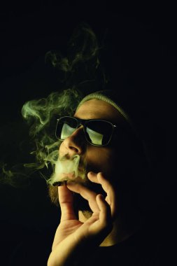 Siyah arka planda beyaz hippi bir sakallının portresi. Stüdyo stok fotoğraf konsepti sigara ve marihuana.