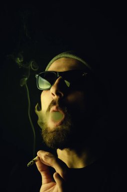 Siyah arka planda beyaz hippi bir sakallının portresi. Stüdyo stok fotoğraf konsepti sigara ve marihuana.