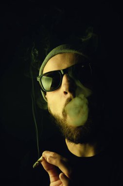 Siyah arka planda beyaz hippi bir sakallının portresi. Stüdyo stok fotoğraf konsepti sigara ve marihuana.