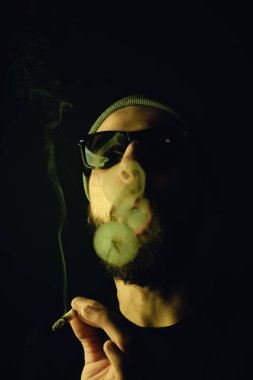 Siyah arka planda beyaz hippi bir sakallının portresi. Stüdyo stok fotoğraf konsepti sigara ve marihuana.