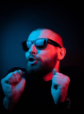Neon tarzı karizmatik bir adamın stüdyo portresi. Sakallı bir adamın sürpriz fotoğrafı..