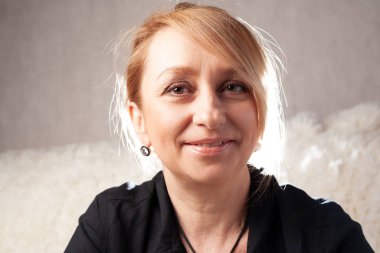 Yetişkin, güzel, ortalama yaşında bir sarışın. Kanepede bir odada güzel bir annenin portresi..