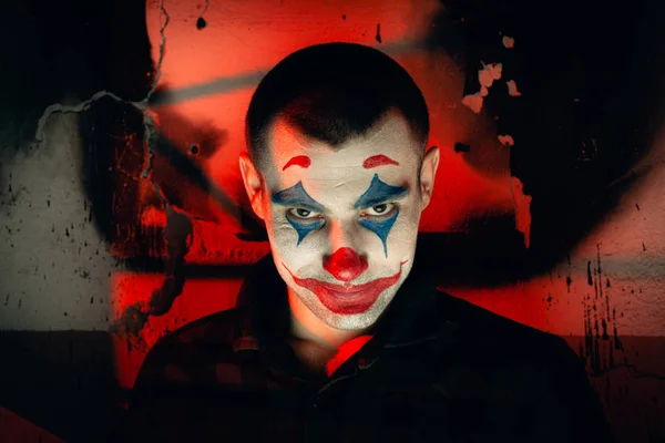 Close-up portrait of a joker man. Stock photo makeup joker in a horror room.