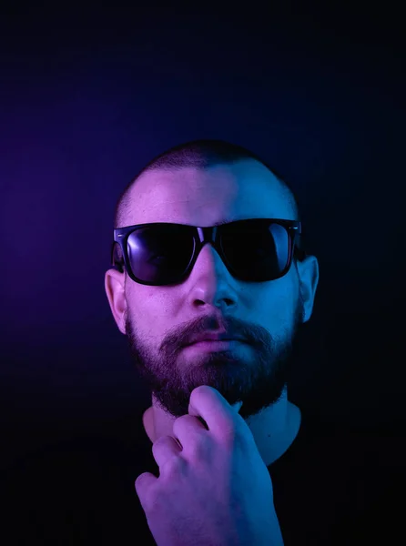 Portrait of a hipster guy with color light. Hipster face portrait in studio.