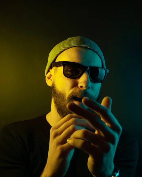 Portrait of a hipster guy with color light. Hipster face portrait in studio.