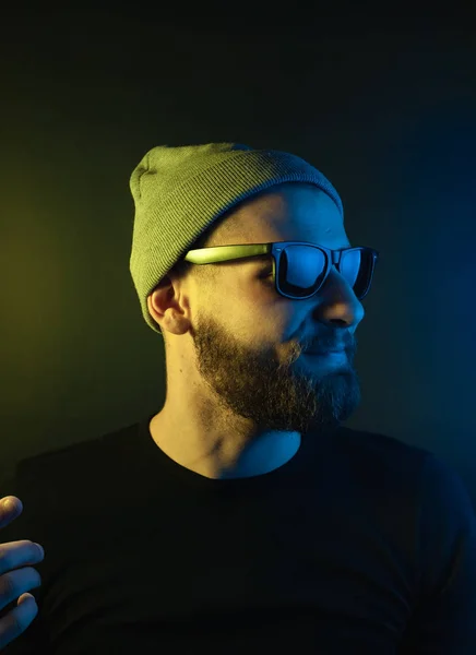 Portrait of a hipster guy with color light. Hipster face portrait in studio.