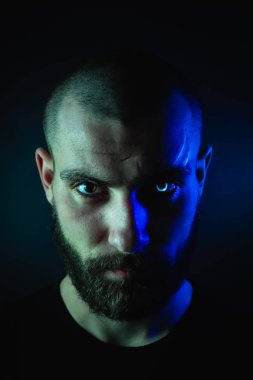 Kurt adam portresi, yüzünde yara izi ve parlayan bir göz olan bir yüz..
