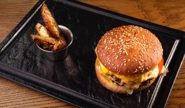 Ahşap bir masa ve siyah bir tepside üst manzara hamburgeri..