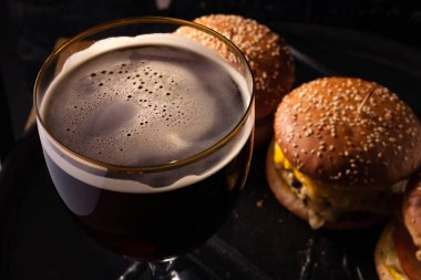 Bardakta soğuk bira ve sulu büyük hamburger şeklinde atıştırmalık. Fast food.